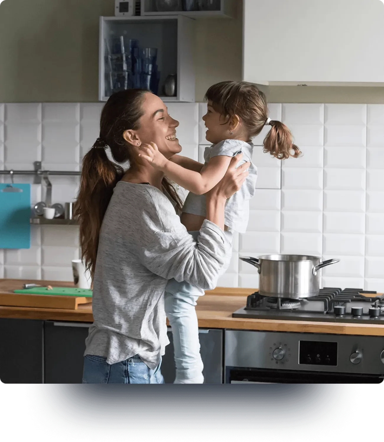 A woman holds her child while in the kitchen