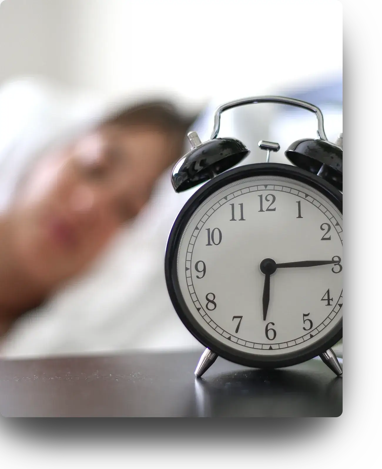 a woman sleeping alongside an alarm clock