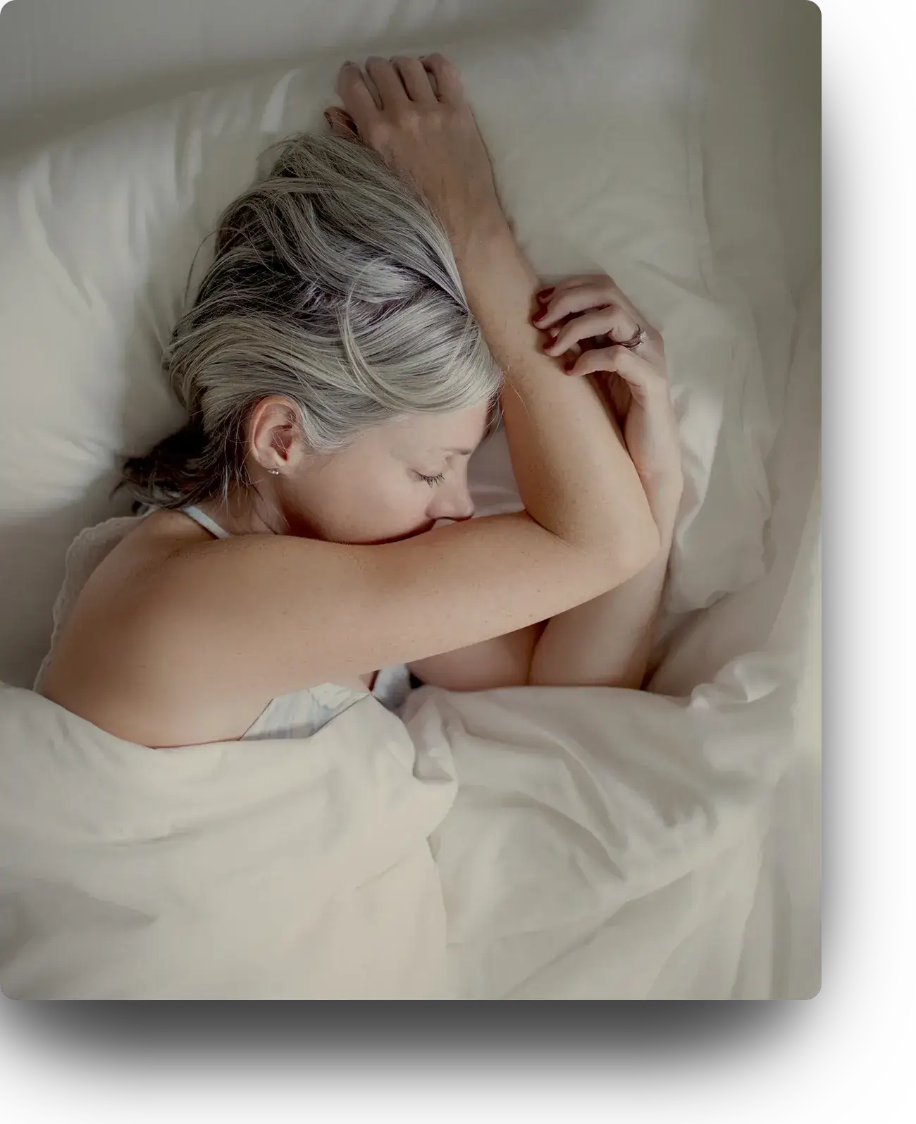 a woman sleeping peacefully on a white bed