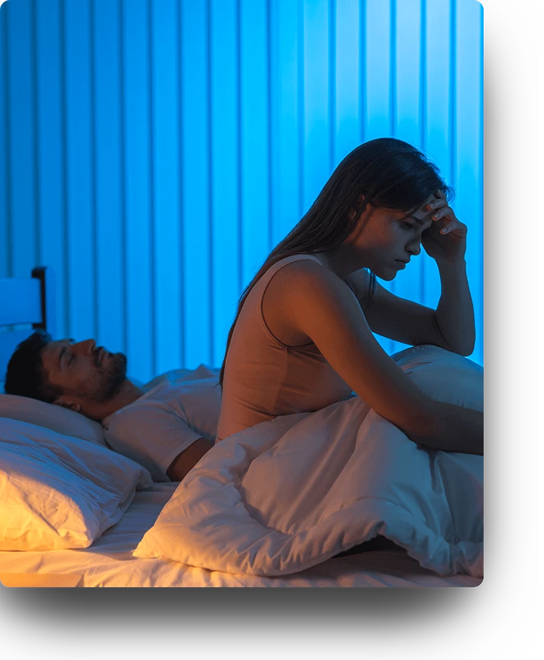 Woman awake, looking upset, while her partner is sleeping. 